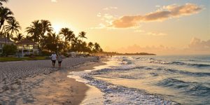 Couple walking along a tranquil beach at sunset.